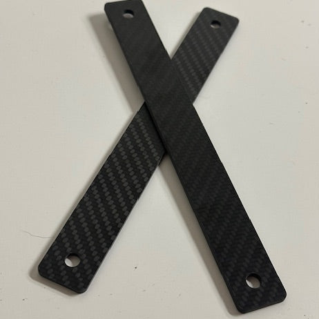 Two carbon fiber strips crossed on a white surface