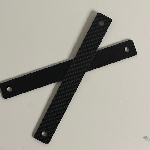 Two carbon fiber strips with holes on a white background